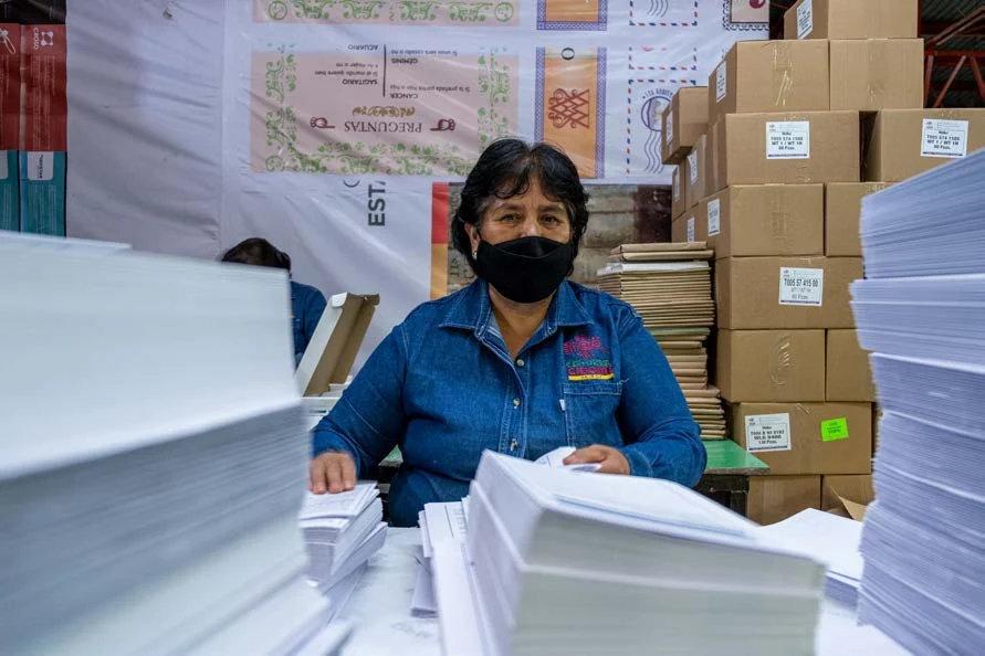 Integrante de Editorial CIGOME organizando material impreso entre cajas y hojas