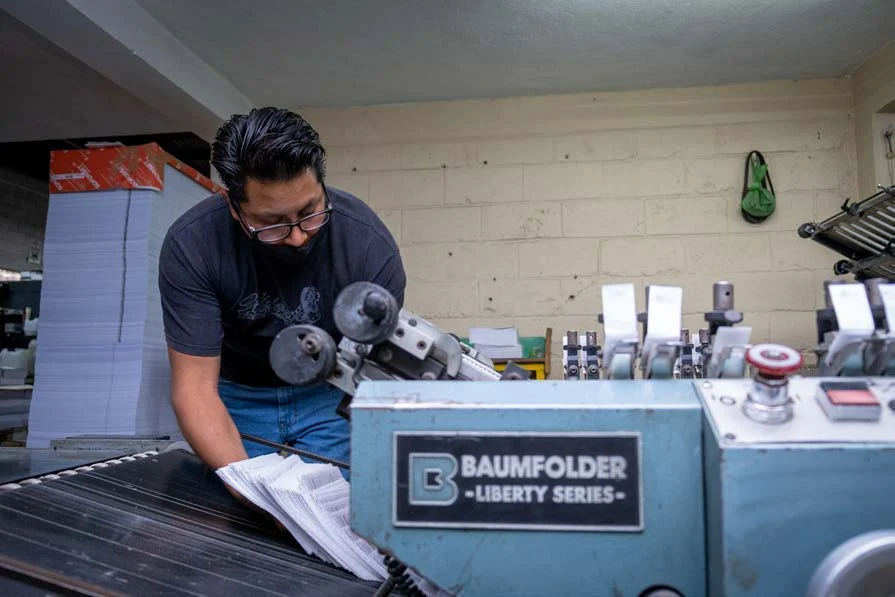Operador revisando una máquina dobladora de papel en Editorial CIGOME