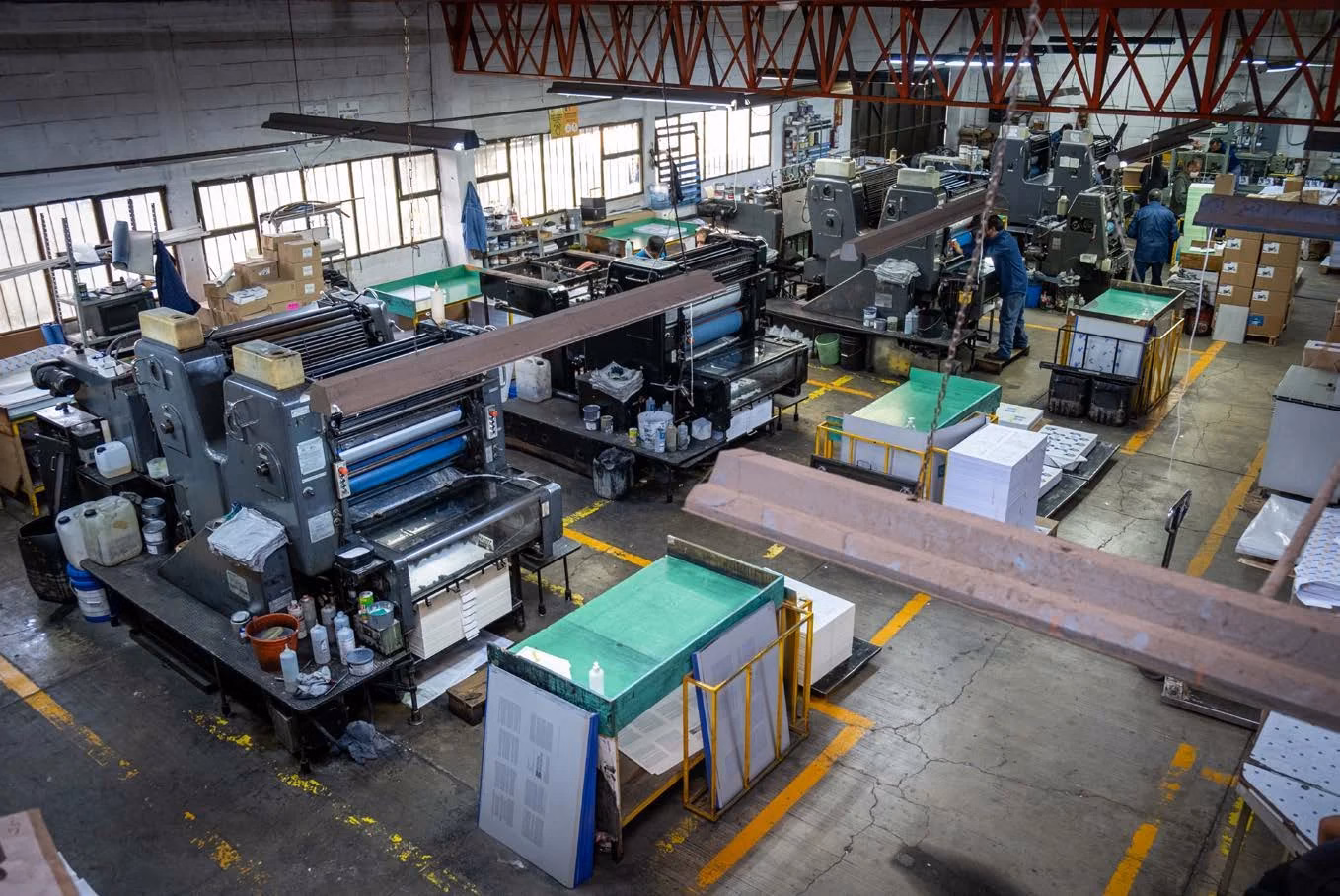 Vista del taller de Editorial CIGOME, imprenta en Toluca, con máquinas de impresión y pilas de papel