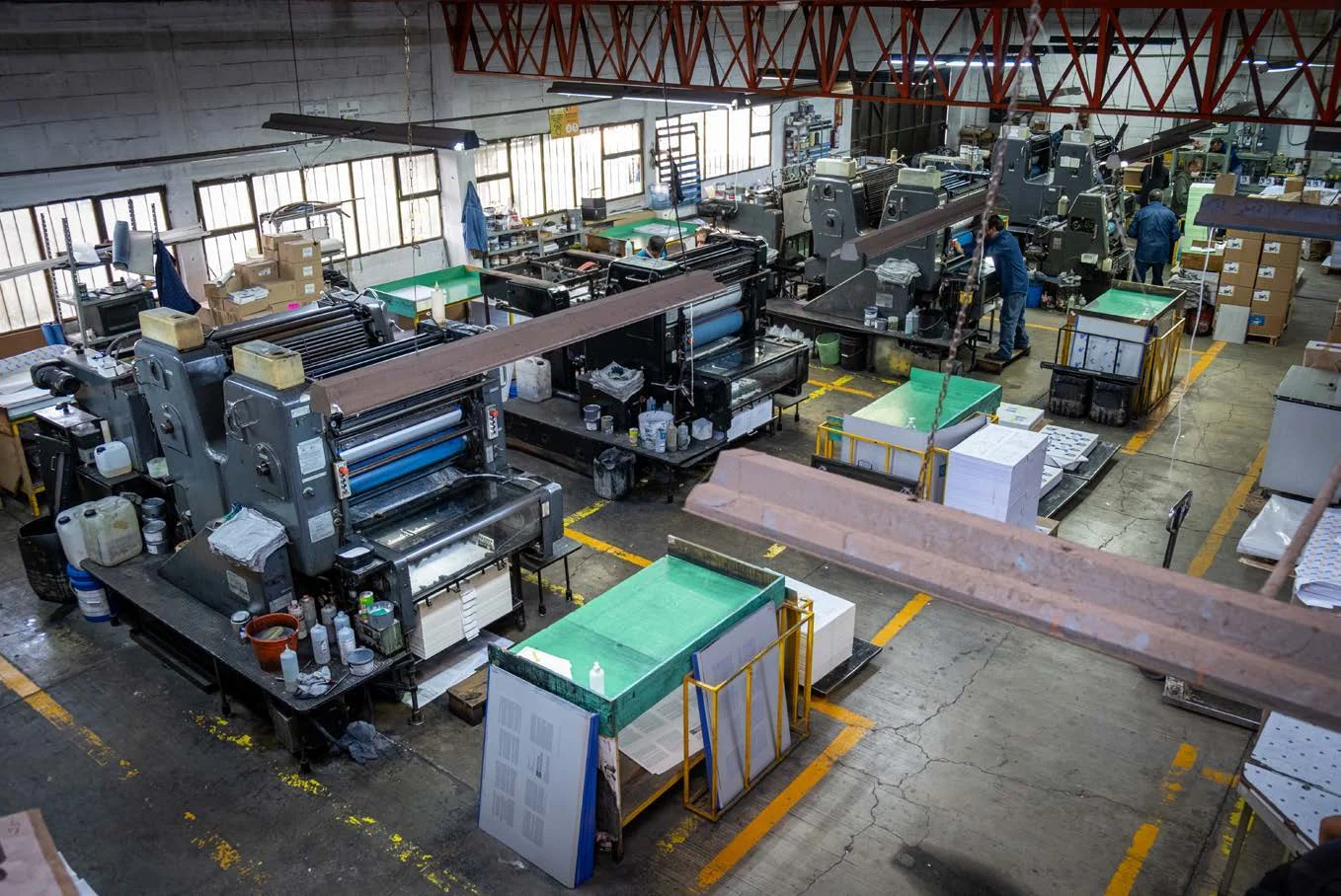 Vista del taller de Editorial CIGOME, imprenta en Toluca, con máquinas de impresión y pilas de papel